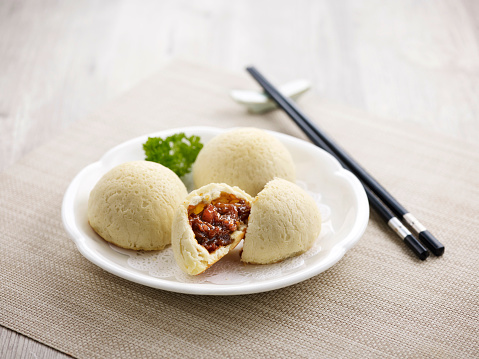 Crispy BBQ Honey Pork Bun with chopsticks Served in a dish isolated on wooden board side view on grey background