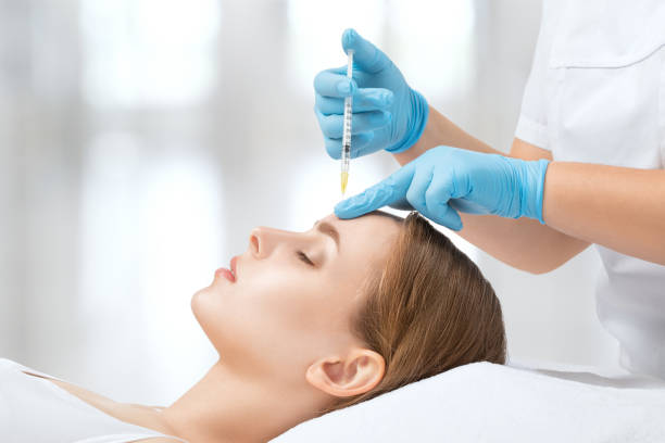 Cosmetologist makes rejuvenating anti wrinkle injections on the face of a beautiful woman. Female aesthetic cosmetology in a beauty salon. stock photo