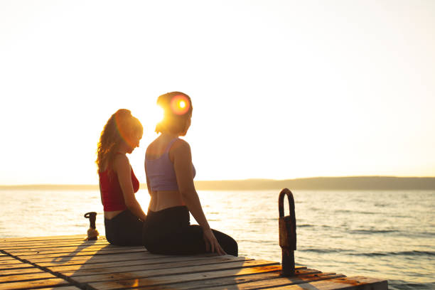 best girlfriends sitting on the pier at sunset
