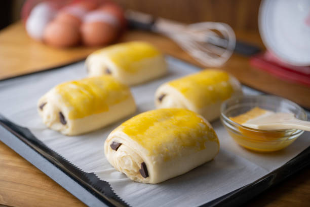 spreading egg yolk on chocolate croissants, pastry image