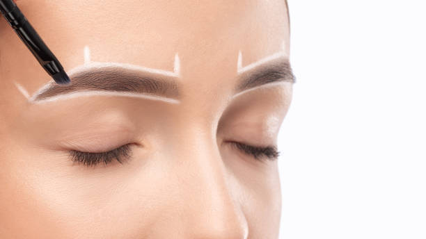 istock Make-up artist makes markings with white pencil for eyebrow and paints eyebrows. Professional makeup and facial care. 1403126692