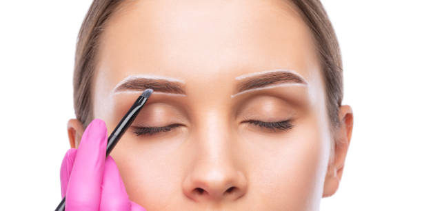 istock Make-up artist makes markings with white pencil for eyebrow and paints eyebrows. Professional makeup and facial care. 1403126740