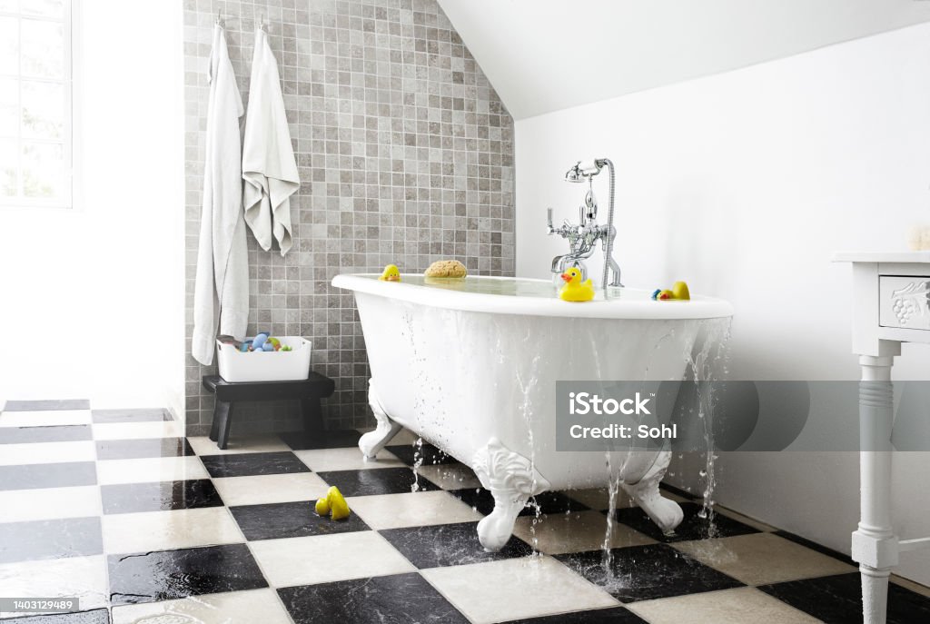 Wet bathroom Bright bathroom. the water runs over the bathtub down to the floor. water damage to the floor Overflowing Stock Photo