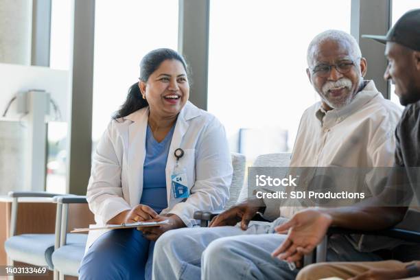 Senior man and young adult son enjoy talking with doctor