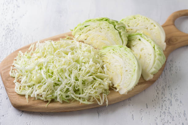 White young cabbage, chopped into strips and cut into segments on a wooden board, light blue background. Cooking a delicious healthy salad or other vegan dish White young cabbage, chopped into strips and cut into segments on a wooden board, light blue background, top view. Cooking a delicious healthy salad or other vegan dish white cabbage stock pictures, royalty-free photos & images