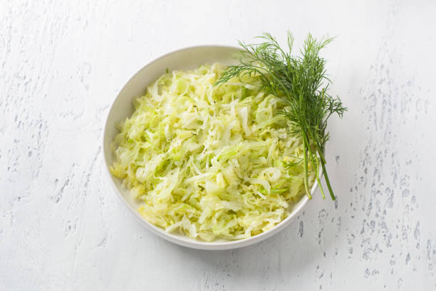 istock Steam white cabbage in a white ceramic bowl with herbs and green sauce on a light blue background, top view. Delicious diet food 1403137919