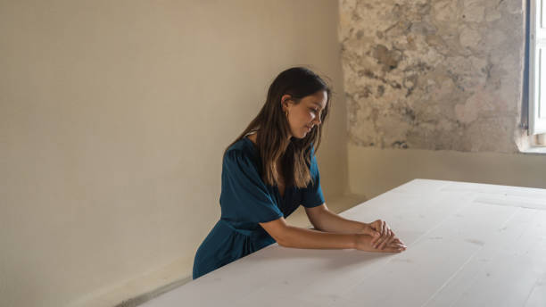 istock Young woman sits at empty long, white table indoors 1403139989