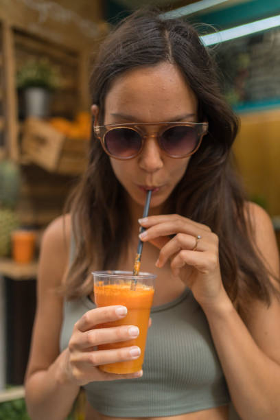 istock Young woman drinks fresh orange juice outdoors 1403140077