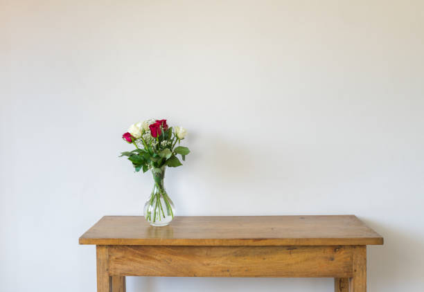 Red and cream roses in glass vase on oak side table