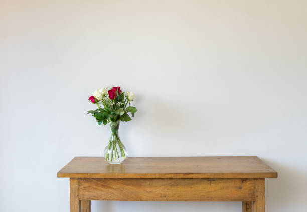 красные и кремовые розы в стеклянной вазе на дубовой тумбочке - side table стоковые фото и изображения