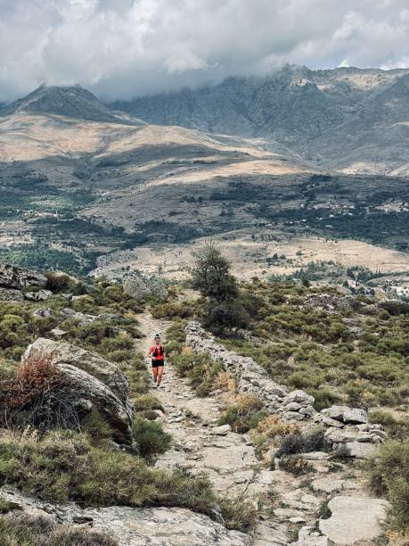 istock Young woman hikes up arid mountain side, lofty clouds 1403141415