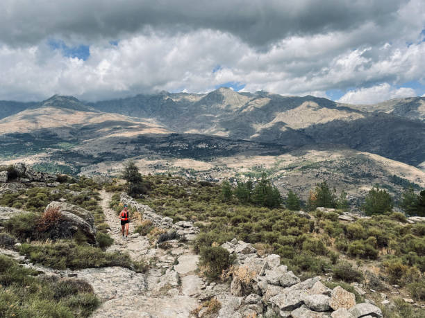 istock Young woman hikes up arid mountain side, lofty clouds 1403141456
