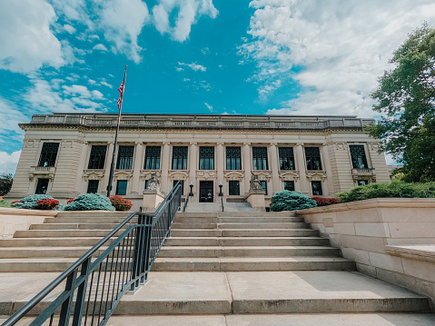 Front View of the Illinois Supreme Courthouse in Springfield, IL, USA on a Summer day. Low-angle view looking up from the bottom of the steps. American flag stands in front of this majestic building.