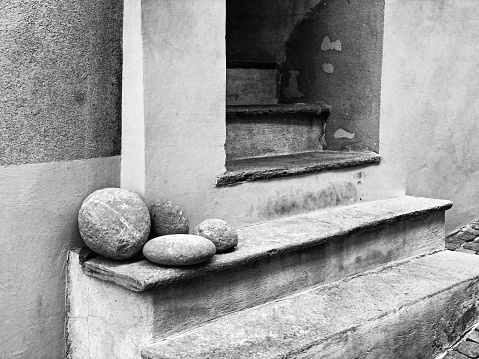 Four stones are placed near the entrance to a home in the small town of Barolo in the Piedmont area of Italy. In black and white.