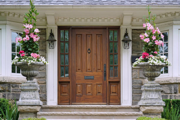 House entrance with elegant wood grain front door and tall flower pots stock photo