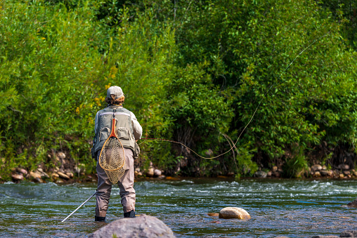 A senior woman fly-fishing in a river in Utah