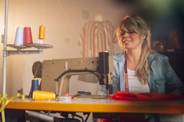 istock Tailor woman sitting and sewing on a sewing machine a in studio 1403148886