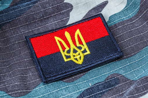 Fabric curved flag of Ukraine, UA. Blue and yellow colors.Ukraine patch on army uniform.Stop war.Patriotism.Concept of Ukraine.Democracy and politics. Close up shot, background