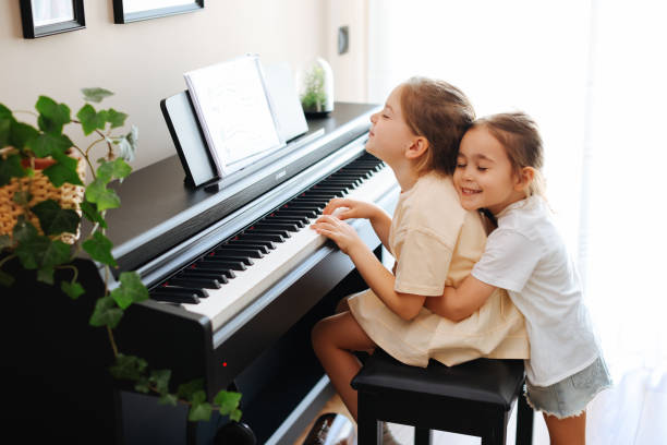 two sisters having fun practicing piano together - practicing piano child playing imagens e fotografias de stock