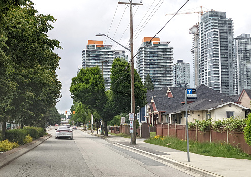 Surrey, Canada - June 12, 2022: Looking east along 104th Avenue near132nd Street in the Whalley neighborhood. Traditional detached houses and modern condo towers line this residential district of Surrey City Centre. Cloudy spring morning in Metro Vancouver.