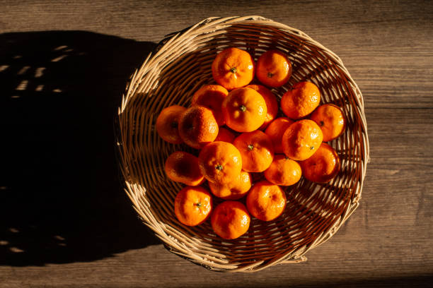 istock Oranges in a wicker basket, Sun shines to create light and shadow, Top view. 1403153214