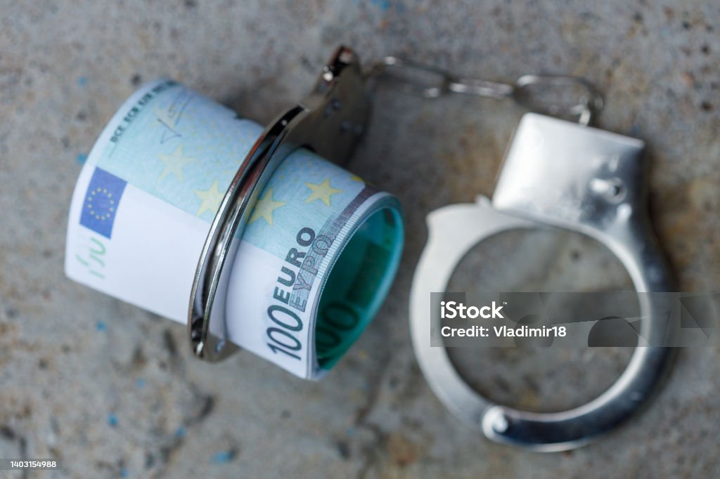 a pack of one hundred euro banknotes in handcuffs a pack of one hundred euro banknotes in handcuffs. High quality photo Arrest Stock Photo