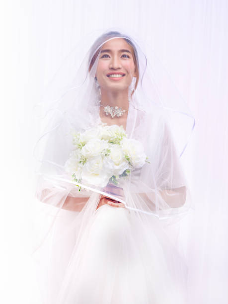 istock bride in white gown with veil holding flower bouquet 1403158196