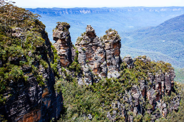 Close-up Color Photograph of the Three Sisters Rock Formation in the Blue Mountains of Australia on a partly cloudy day.
