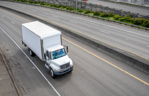 Powerful compact meddle size rig semi truck with box trailer driving on the highway road with exit intersection stock photo