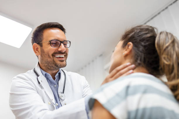 Endocrinologist examining throat of young woman in clinic. Women with thyroid gland test . Endocrinology, hormones and treatment. Inflammation of the sore throat Endocrinologist examining throat of young woman in clinic. Women with thyroid gland test . Endocrinology, hormones and treatment. Inflammation of the sore throat thyroid disease stock pictures, royalty-free photos & images