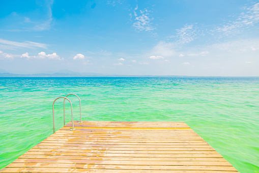 Ramp and ladder to the beach by clear sea water.