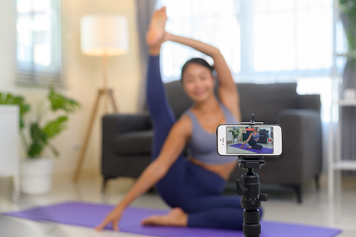 A Professional yoga coach teaching online training class to students during live streaming on social media, healthcare concept
