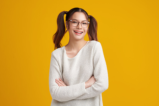Beautiful young asian women smiling and wearing trendy glasses, isolated on yellow background,