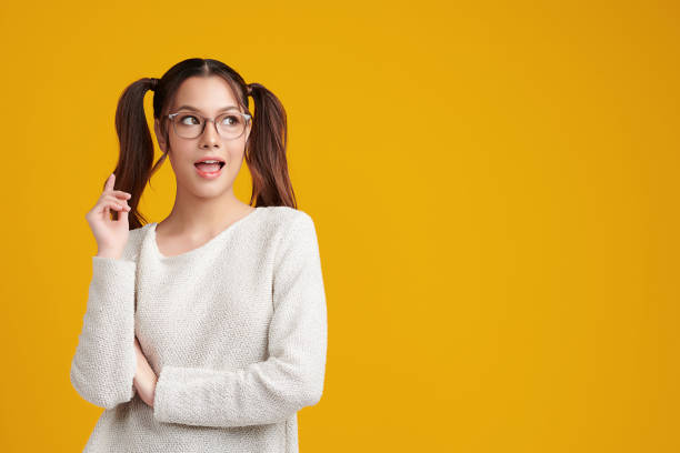 istock Curious Asian girl is thinking and standing on yellow background with curious face, blank copy space for your advertising content. 1403189145