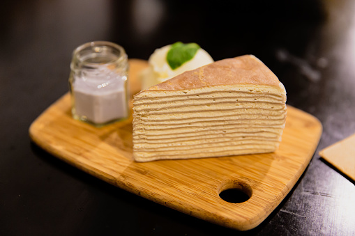 Mille crepe cake with taro sauce, vanilla bean ice cream on the chopping board in the restaurant, selective focus