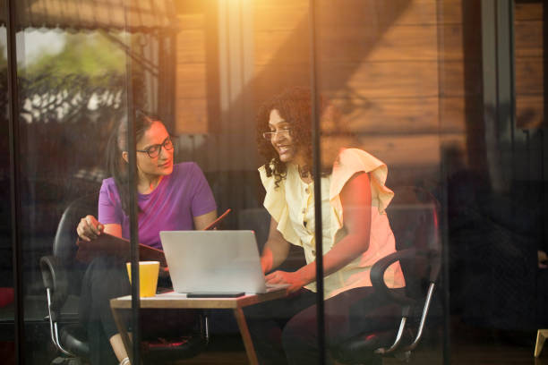 istock Two female colleagues using laptop at cafe 1403195957