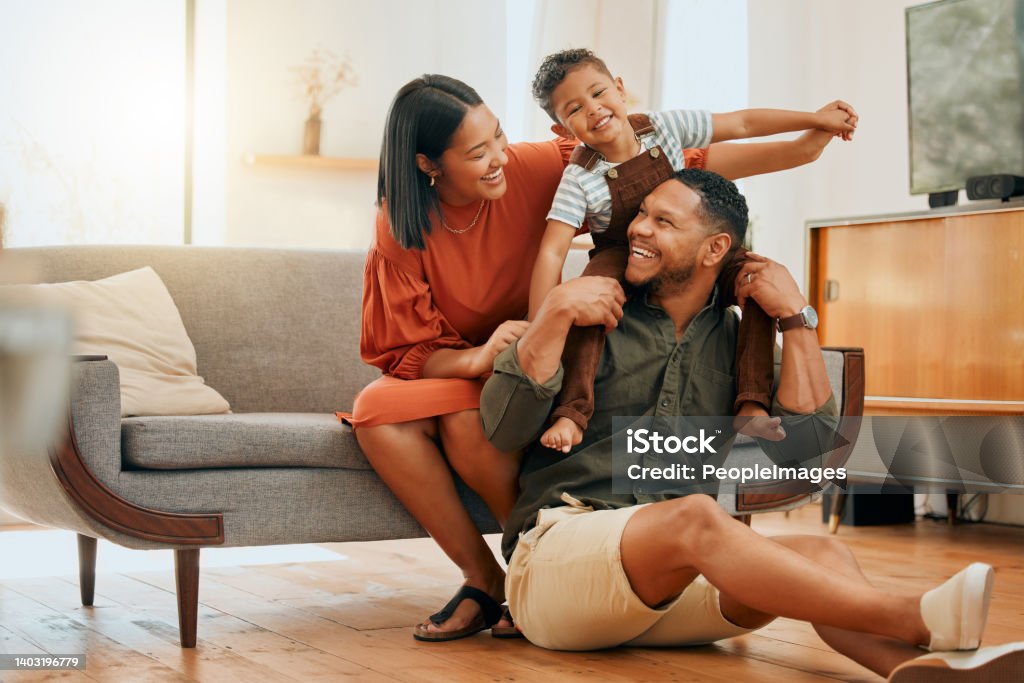 A happy mixed race family of three relaxing in the lounge and being playful together. Loving black family bonding with their son while playing fun games on the sofa at home Family Stock Photo