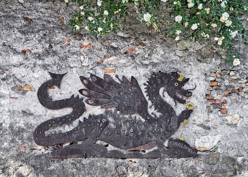 Finalborgo, Italy - May 11, 2022: A metal dragon on a wall at the entrance to Finalborgo, Italy.