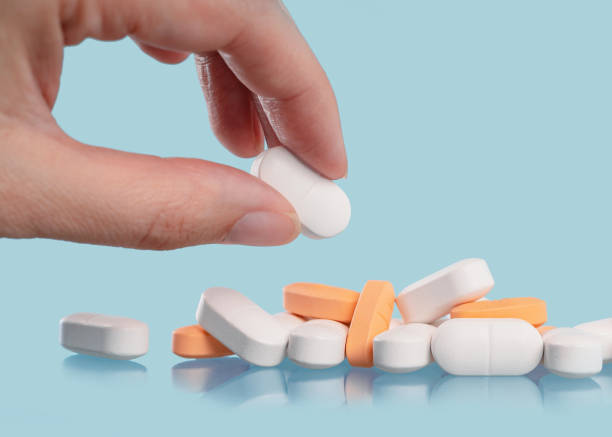 istock Handf with white tablets or pills on blue table. Medicine and pharmacy 1403198246
