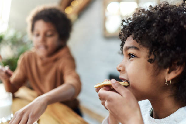 Cute black girl eating pancake at home.