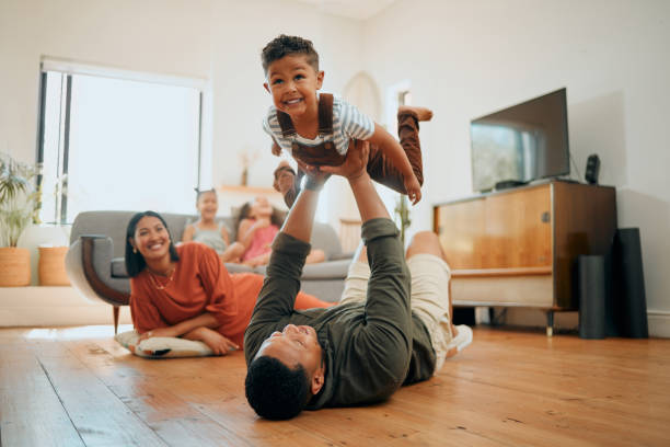 eine glückliche gemischtrassige fünfköpfige familie, die sich in der lounge entspannt und zusammen verspielt ist. liebe schwarze familie, die sich mit ihrem sohn verbindet, während sie zu hause lustige spiele auf dem boden spielt - playful mother playing daughter stock-fotos und bilder