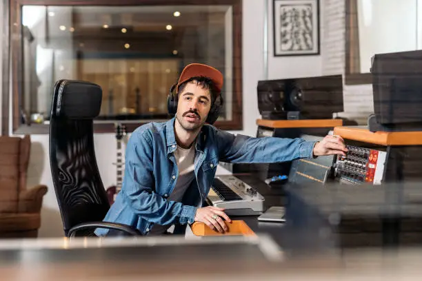 Stock photo of male music producer working with black singer in cool music studio.