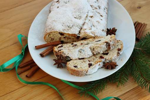Traditional german sweet bread with raisins and candied fruits called Stollen on a plate on wooden table