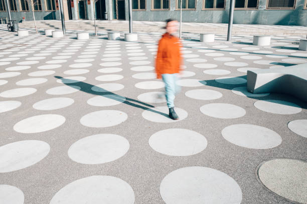 motion blur of girl in red jacket going on asphalted town square with white dots in berlin