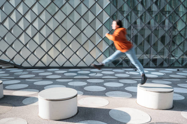 istock motion blurred  woman jumping from bench to bench on white spotted town square 1403203743