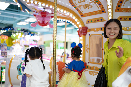 Portrait of a cute elementary age Eurasian girl of Filipino descent smiling directly at the camera while riding on a carousel.