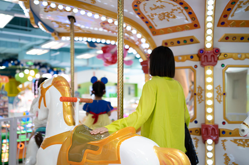 A beautiful woman rides a merry go round with her child