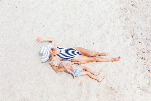 woman and kid sunbathing on the tropical beach