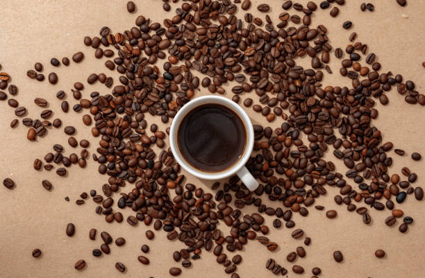 istock Cup of coffee with coffee beans on paper background. Top view 1403207446