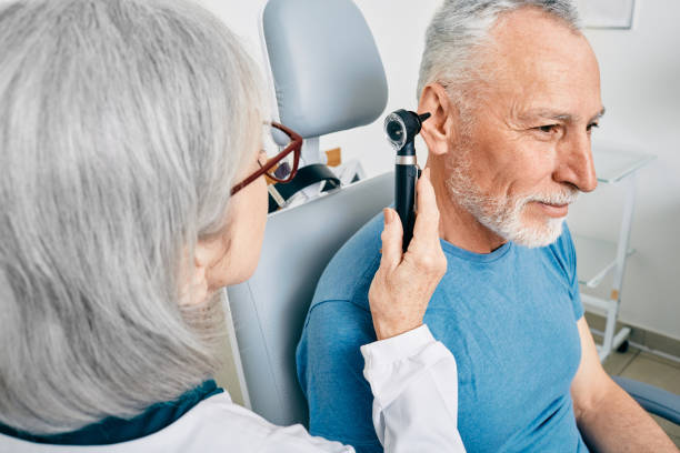 médico otorrinolaringólogo que revisa el oído de un hombre mayor con otoscopio o auriscopio en el centro auditivo. audiología - otoscopio fotografías e imágenes de stock